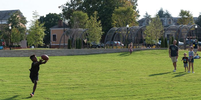 Josh Bergeron / Salisbury Post - Judah Jones, left,  stretches out to catch a pass from his dad, Kevin Jones, in the background. The Joneses spent time Friday afternoon at the new Bell Tower Green Park.